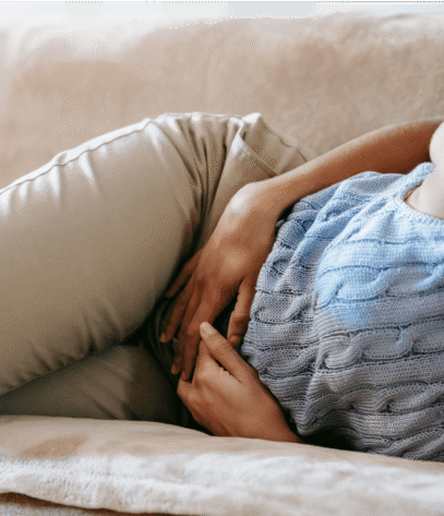 Photo d'une femme allongée sur un canapé qui a mal au ventre